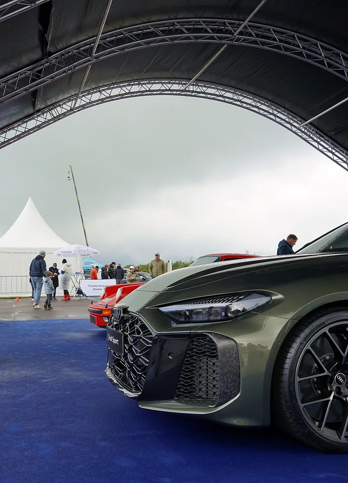 Dunkelgrüner Audi E-tron GT mit großen Rädern steht unter einem Zelt, im Hintergrund weitere Autos und Besucher des Fuchsfelgen-Treffens.