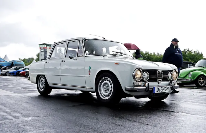Weißer Alfa Romeo Giulia aus den 1960er Jahren mit Fuchsfelgen auf einem Oldtimertreffen.