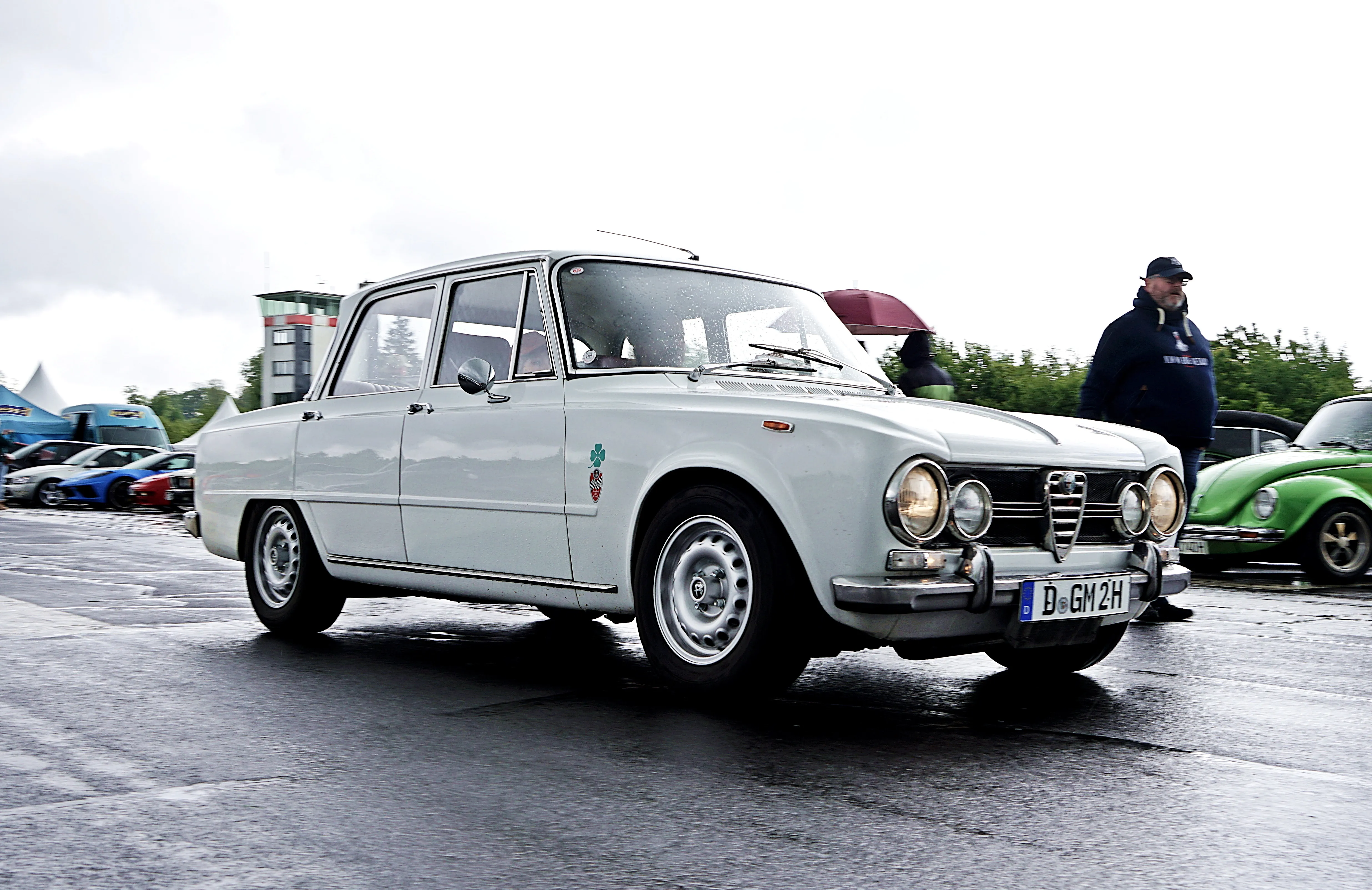 Weißer Alfa Romeo Giulia aus den 1960er Jahren mit Fuchsfelgen auf einem Oldtimertreffen.