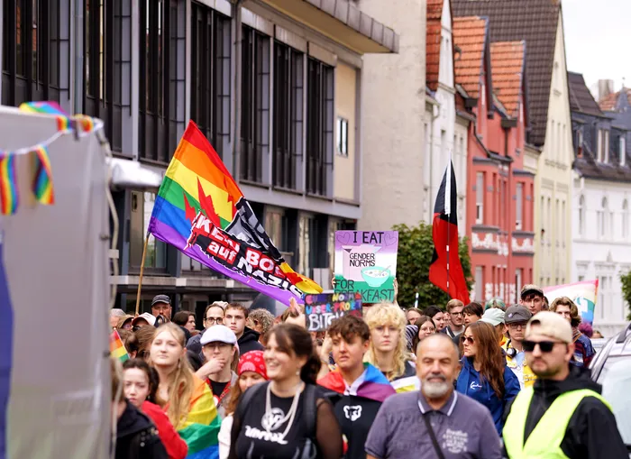 Eine Menschenmenge bei einer Demonstration, eine Person hält eine große Regenbogenfahne mit der Aufschrift 'Kein Bock auf Nazis'.