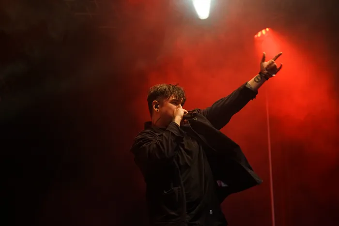 Ein Musiker der Band Callejon performt auf einer Bühne unter rotem Licht und Nebel mit erhobener Hand.
