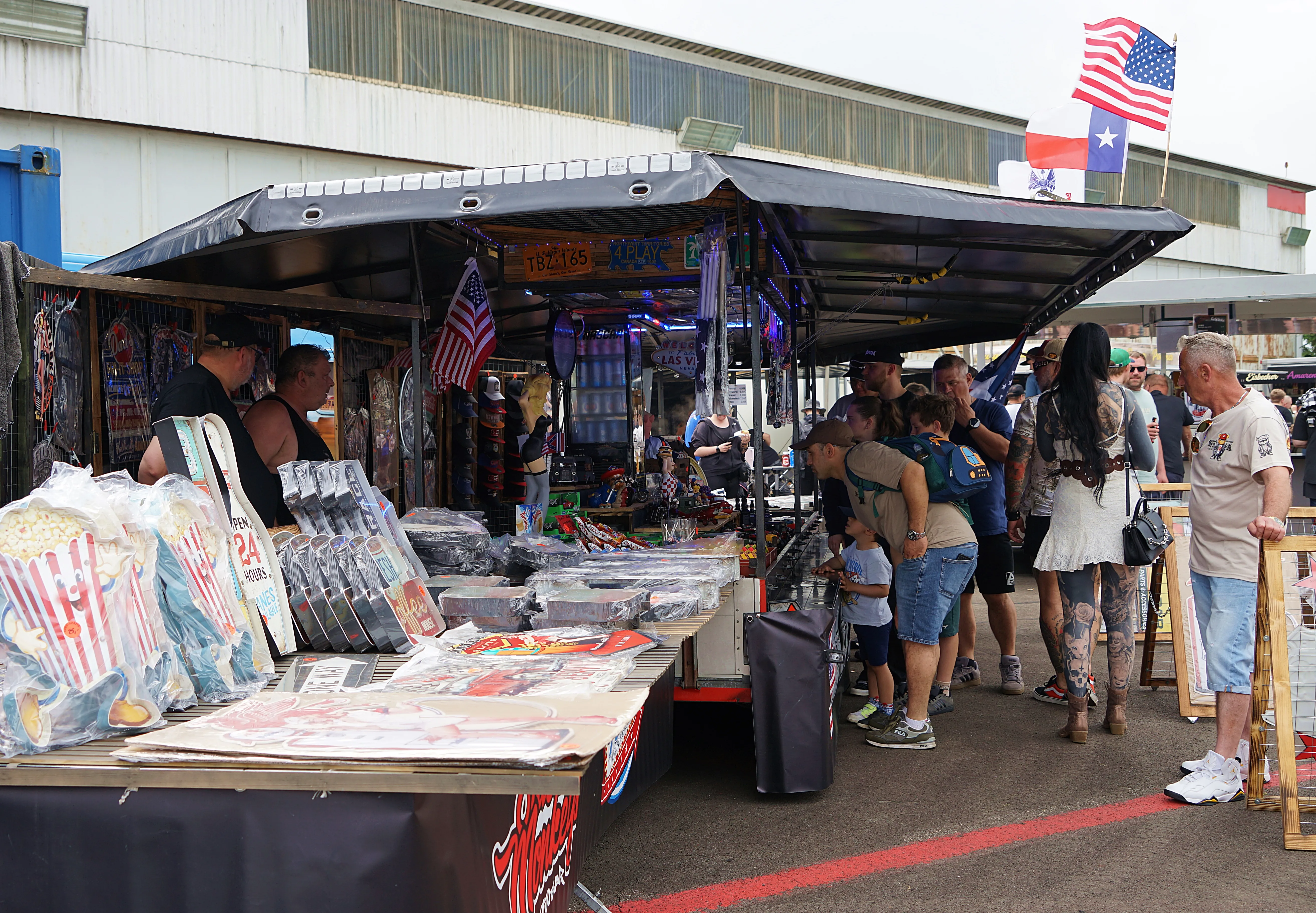 Ein belebter Marktstand mit Souvenirs, Sammelkarten und patriotischen Artikeln zieht eine vielfältige Besuchergruppe an.