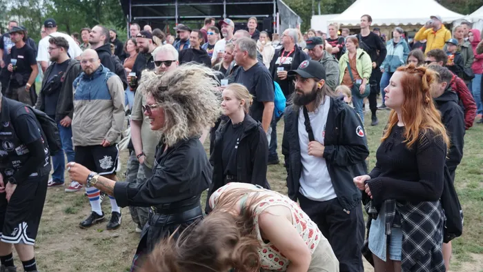 Eine Menschenmenge bei einem Open-Air-Event vor der Collabo Stage, im Vordergrund eine Frau mit voluminösem, lockigem Haar.