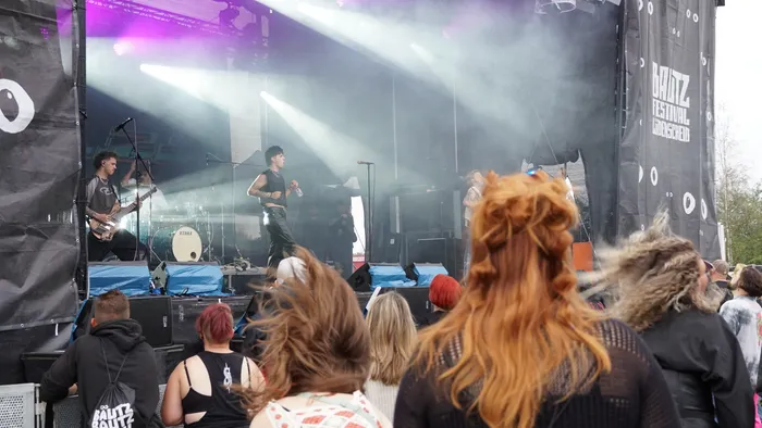 Eine Band spielt auf einer hell erleuchteten, vernebelten Bühne vor einem Publikum.
