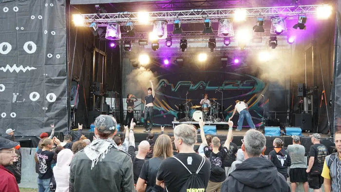 Die Band Avralize spielt auf einer hell erleuchteten Bühne mit Nebel vor einem Publikum.