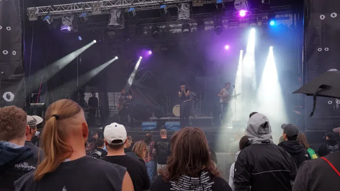 Die Band Avralize tritt auf der Collabo Stage unter violetten und weißen Scheinwerferstrahlen vor einer Zuschauermenge auf.