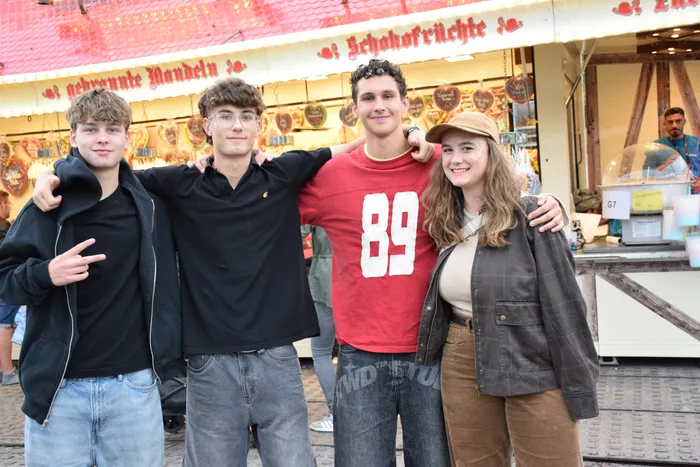 Vier junge Menschen posieren lächelnd mit den Armen umeinander vor einem Marktstand auf dem Bautz-Samstag.