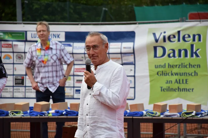 Ein Mann in einem weißen Hemd spricht in ein Mikrofon bei der Jubiläumsfeier der MTC/TC Halver Open.
