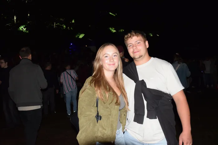 Ein junger Mann und eine junge Frau lächeln bei einer nächtlichen Veranstaltung.