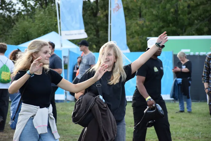 Zwei junge Frauen tanzen mit ausgestreckten Armen auf einer Wiese während des Bautz 2026 Festivals.