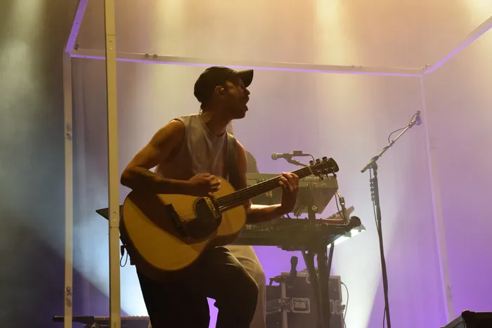 Ein Musiker mit Cap spielt Akustikgitarre und singt unter Bühnenlicht auf der Main Stage.