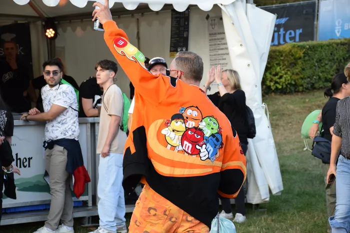 Ein Besucher in einer orangefarbenen Jacke mit M&M-Motiven hebt den Arm bei der Feier zum Bautz 2026.