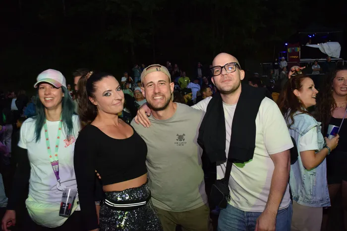 Die Gruppe Knallblech posiert lächelnd bei einer nächtlichen Open-Air-Veranstaltung.