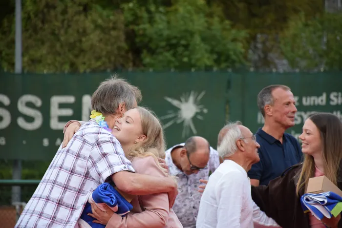 Eine junge Frau umarmt eine ältere Person in einem karierten Hemd während der Jubiläumsfeier der MTC/TC Halver Open.