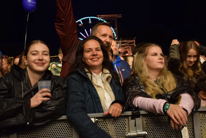 Zuschauer stehen nachts hinter einer Metallabsperrung beim Bautz 2026 Festival, im Hintergrund ist ein beleuchtetes Riesenrad zu sehen.
