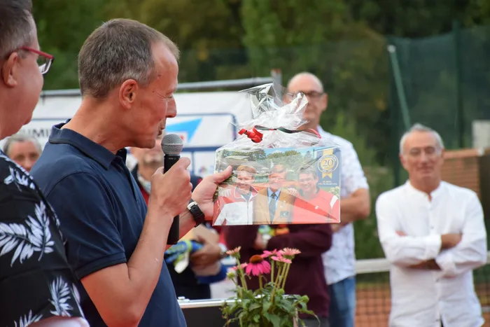 Ein Mann überreicht bei der Feier zum 20-jährigen Jubiläum der MTC/TC Halver Open ein verpacktes Geschenk mit einem Jubiläumsfoto.