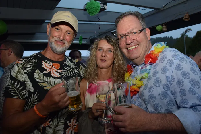 Drei lächelnde Personen stoßen mit Bierkrügen und einem Glas auf das Jubiläum der MTC/TC Halver Open an.