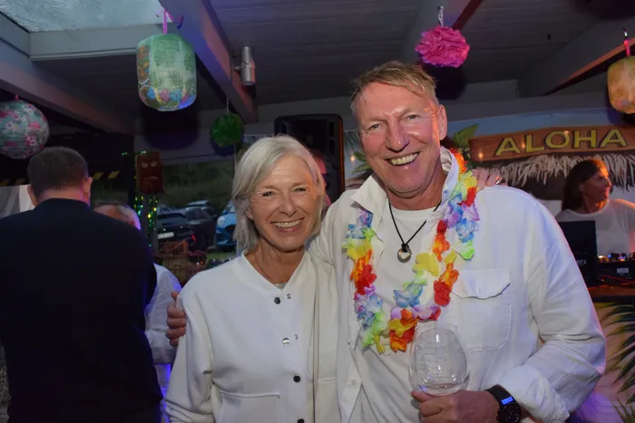 Ein lächelndes Paar, ein Mann mit einer bunten Blumenkette und eine Frau in weißer Kleidung, posiert bei der Jubiläumsfeier der MTC/TC Halver Open.