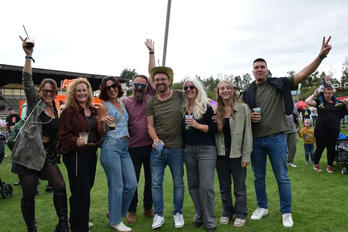 Eine Gruppe lachender Menschen posiert auf einer Wiese beim Bautz Samstag 2026 und hält teilweise Getränke hoch.