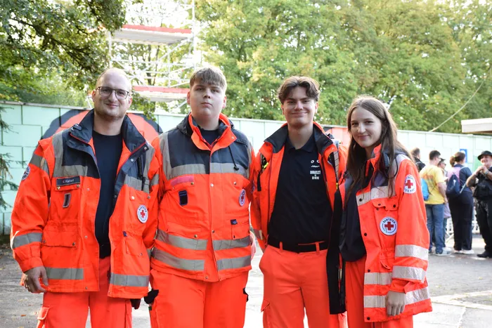 Vier junge Menschen in orangefarbenen Einsatzuniformen mit Reflektoren stehen nebeneinander.