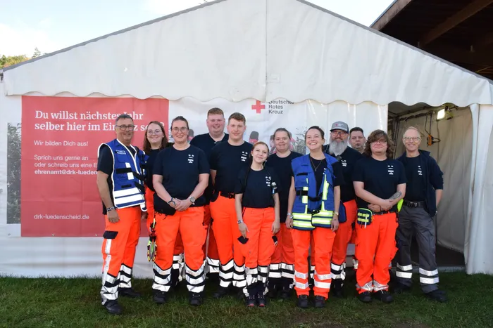 Eine Gruppe von Helfern des Deutschen Roten Kreuzes in Arbeitskleidung posiert vor einem weißen Zelt auf dem Bautz-Festival.