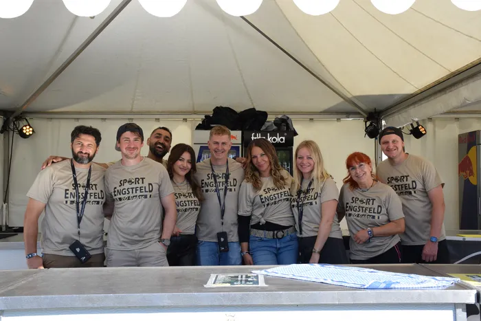 Eine Gruppe von Menschen in einheitlichen „Sport Engstfeld“-T-Shirts steht hinter einem Tresen auf dem Bautz-Festival.
