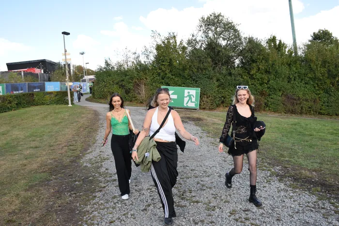 Drei junge Frauen gehen auf einem Schotterweg durch das Gelände des Bautz-Festivals.