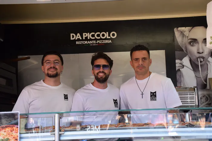 Drei Männer in weißen T-Shirts stehen hinter einer Verkaufstheke des Stalls „Da Piccolo Ristorante-Pizzeria“ auf dem Bautz-Festival.