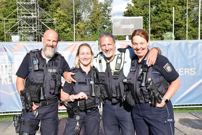 Vier lächelnde Polizistinnen und Polizisten in Uniform posieren gemeinsam vor einem Banner auf dem Bautz-Festival.