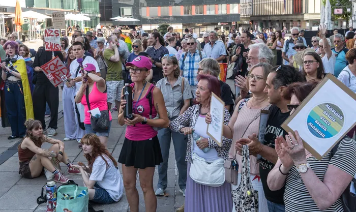 Eine Menschenmenge bei einer Demonstration gegen die AfD in Lüdenscheid hält Protestschilder hoch, unter anderem mit der Aufschrift „Menschen links & rechts Menschen“.
