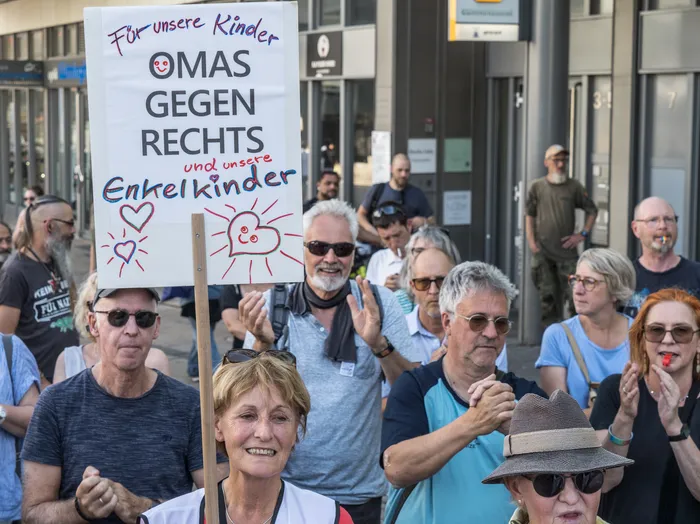 Ein handgeschriebenes Protestschild mit der Aufschrift 'Für unsere Kinder OMAS GEGEN RECHTS und unsere Enkelkinder' wird bei einer Demonstration hochgehalten.