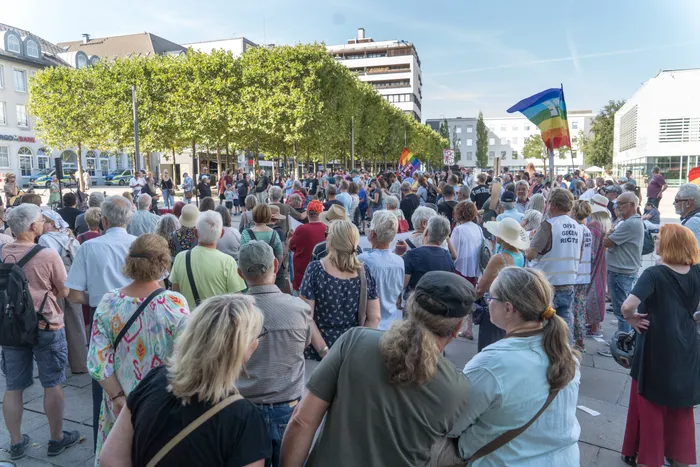 Eine Menschenmenge bei einer Kundgebung mit Regenbogenfahnen auf einem Platz in Lüdenscheid.