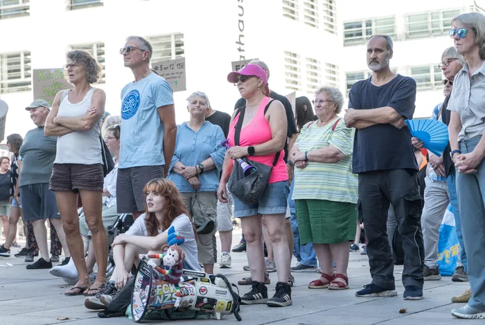 Eine Gruppe von Menschen steht und sitzt bei einer Kundgebung gegen die AfD in Lüdenscheid.