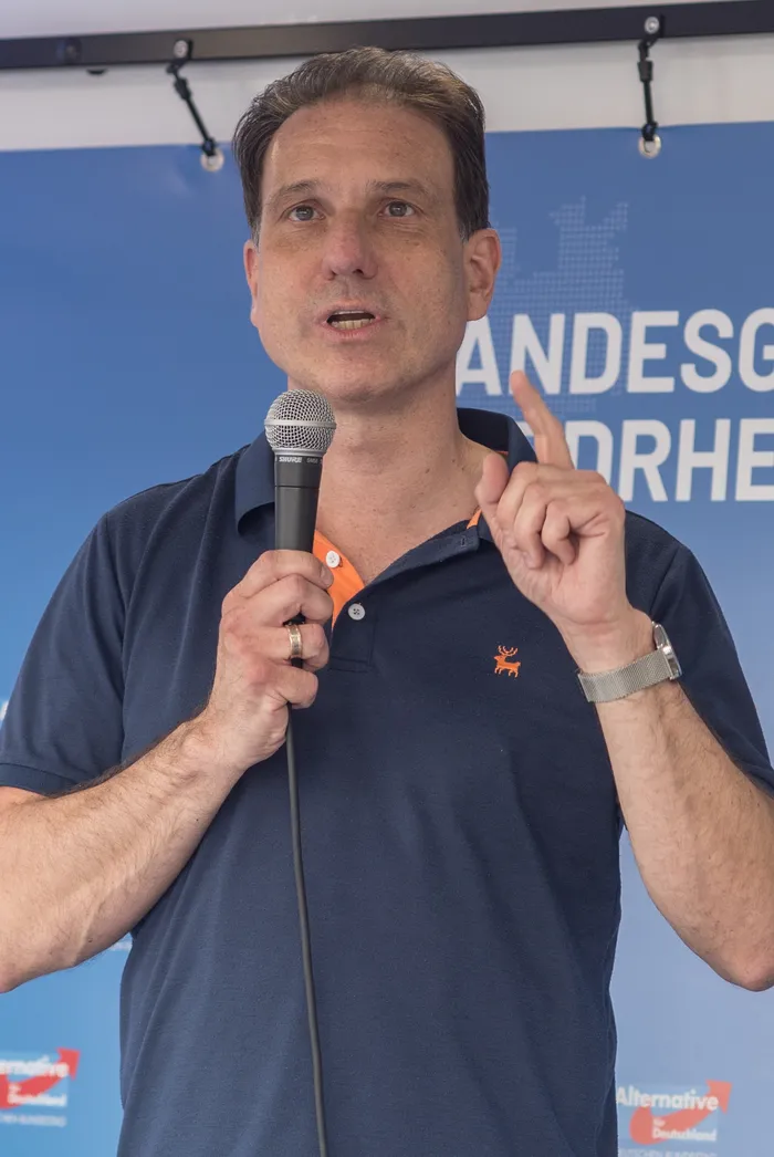 AfD-Redner Christian Loose spricht in ein Mikrofon und hebt dabei den Zeigefinger.