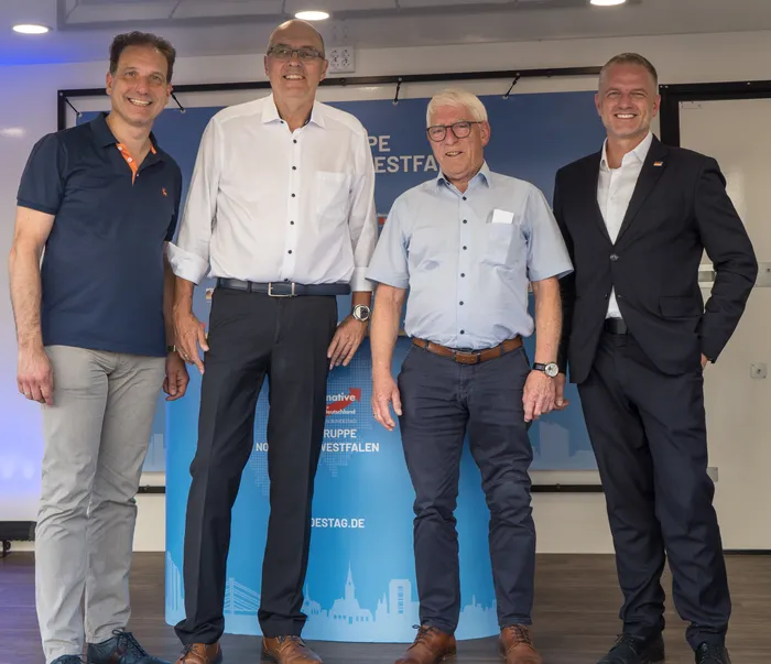 Christian Loose, Peter Bohnhof, Otto Strauß und Adam Balten stehen nebeneinander vor einem blauen Banner.