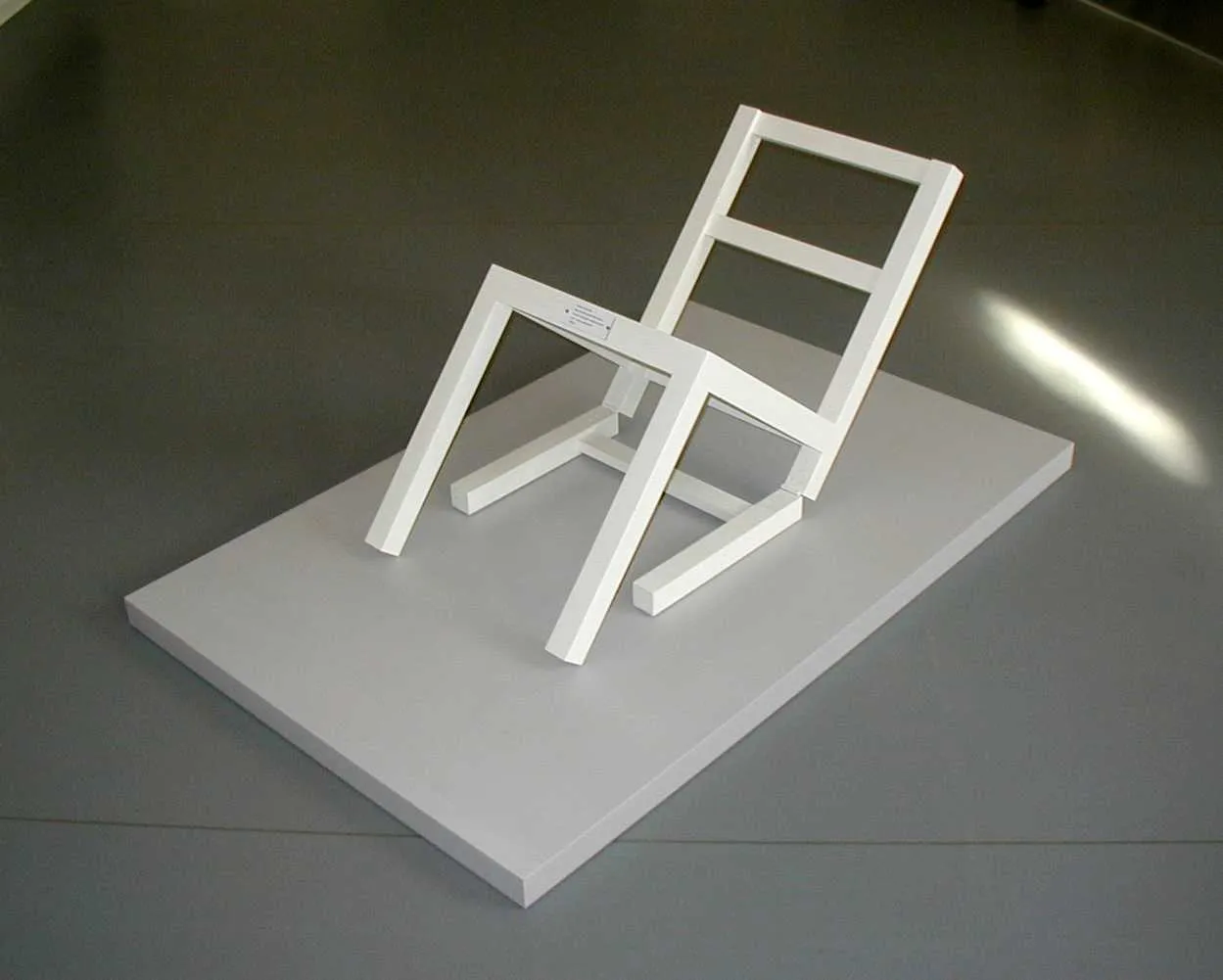 Weißer Stuhl, der scheinbar durch eine schräge Plattform geteilt und in der Luft gehalten wird, Kunstinstallation von Timm Ulrichs aus dem Jahr 1970.