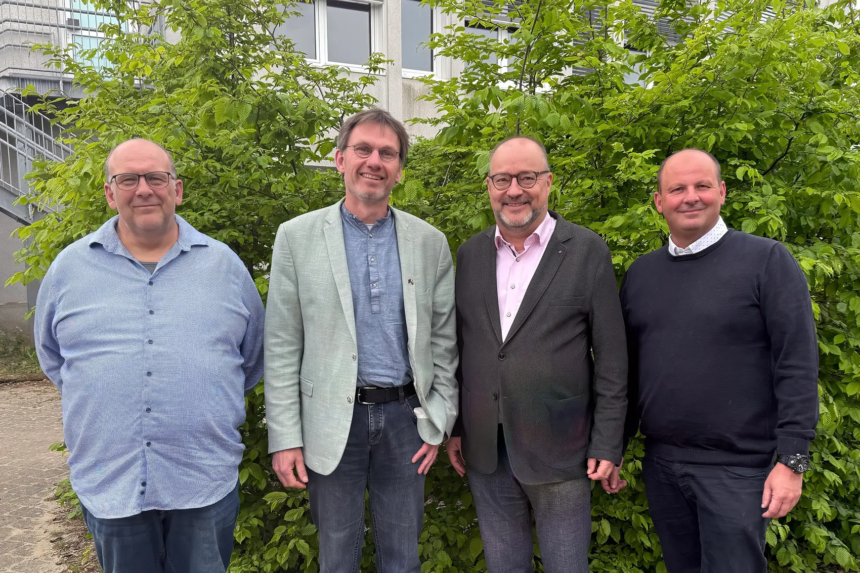Vier Männer stehen nebeneinander vor einem Gebäude mit Büschen im Hintergrund. Von links nach rechts: Sven Schneider, Dr. Christof Grote, Dr. Gregor Kaiser und Dirk Cechelius.
