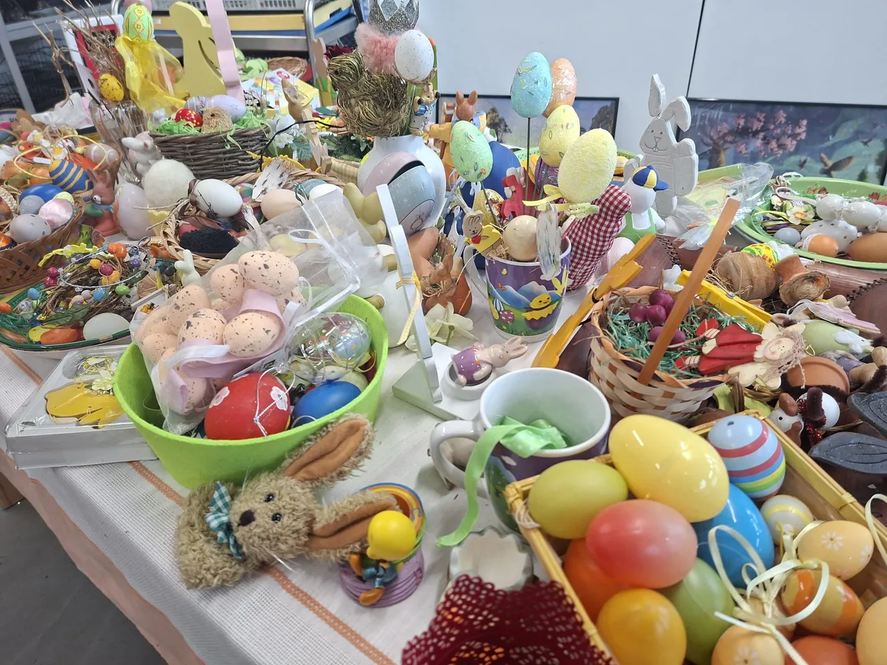 Ein Tisch ist voll mit bunten Ostereiern, kleinen Plüschtieren, Dekorationen und Süßigkeiten.