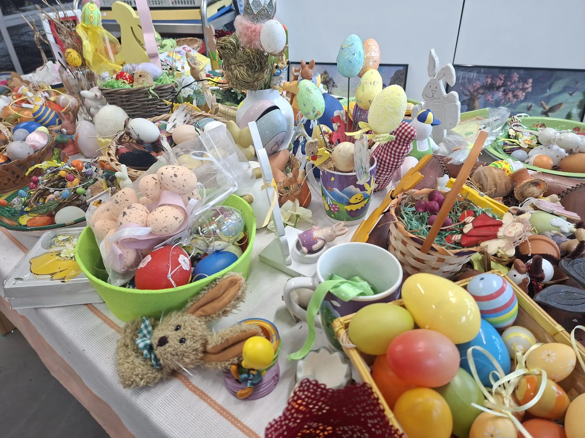 Ein Tisch ist voll mit bunten Ostereiern, kleinen Plüschtieren, Dekorationen und Süßigkeiten.
