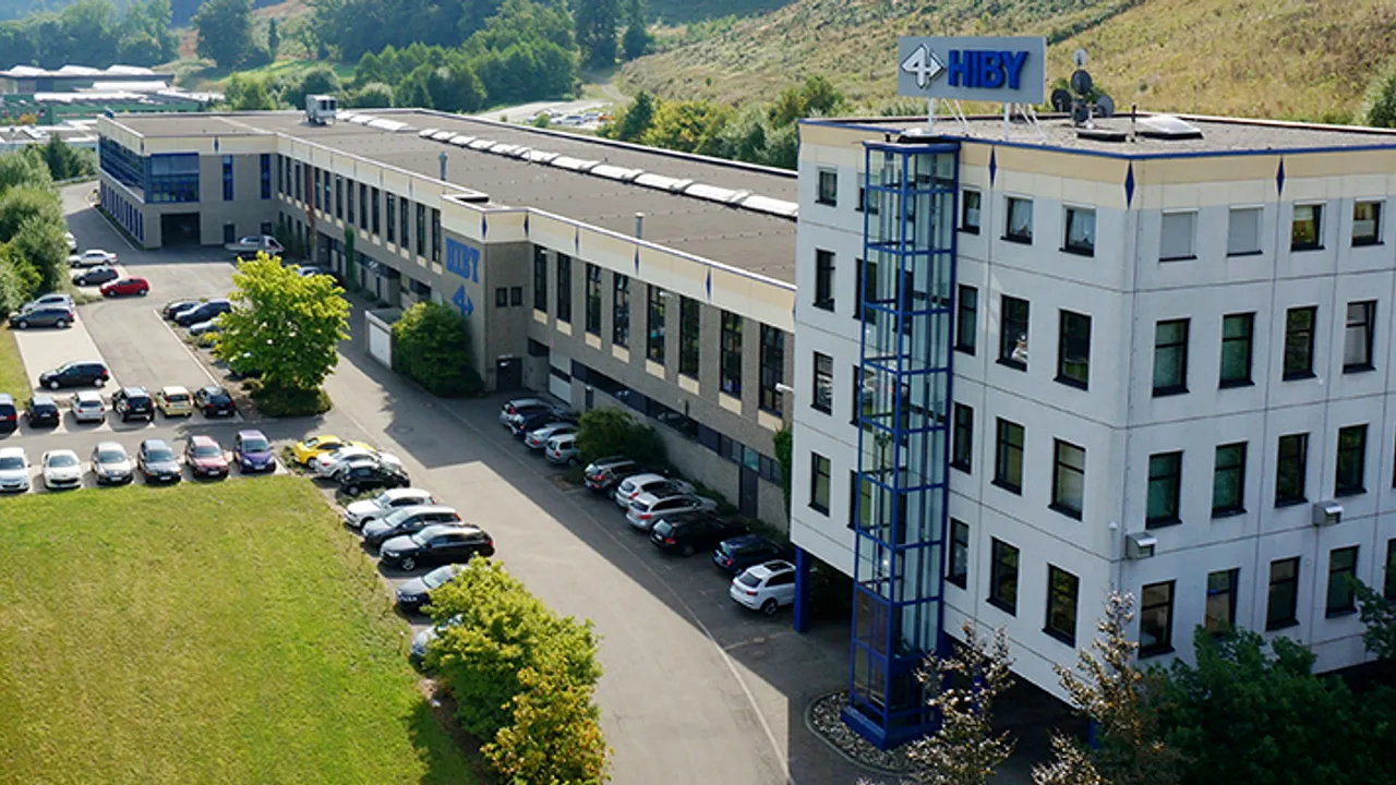 Luftaufnahme des Gebäudekomplexes der Firma Elaflex Hiby mit einem Parkplatz davor.