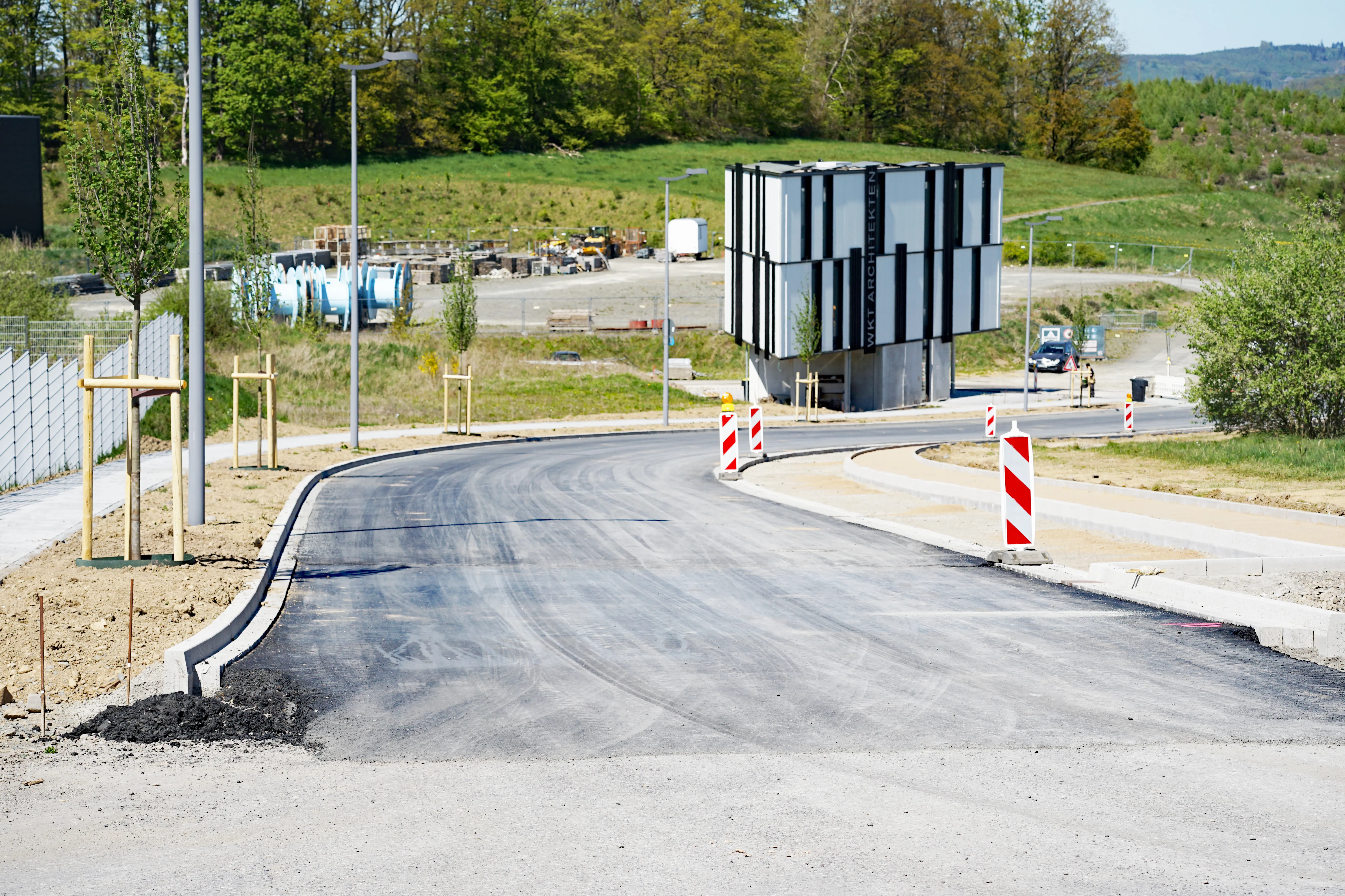 Neuer Straßenverlauf im Gewerbepark Rosmart mit moderner, würfelförmiger Installation und Baustellenmaterialien im Hintergrund.