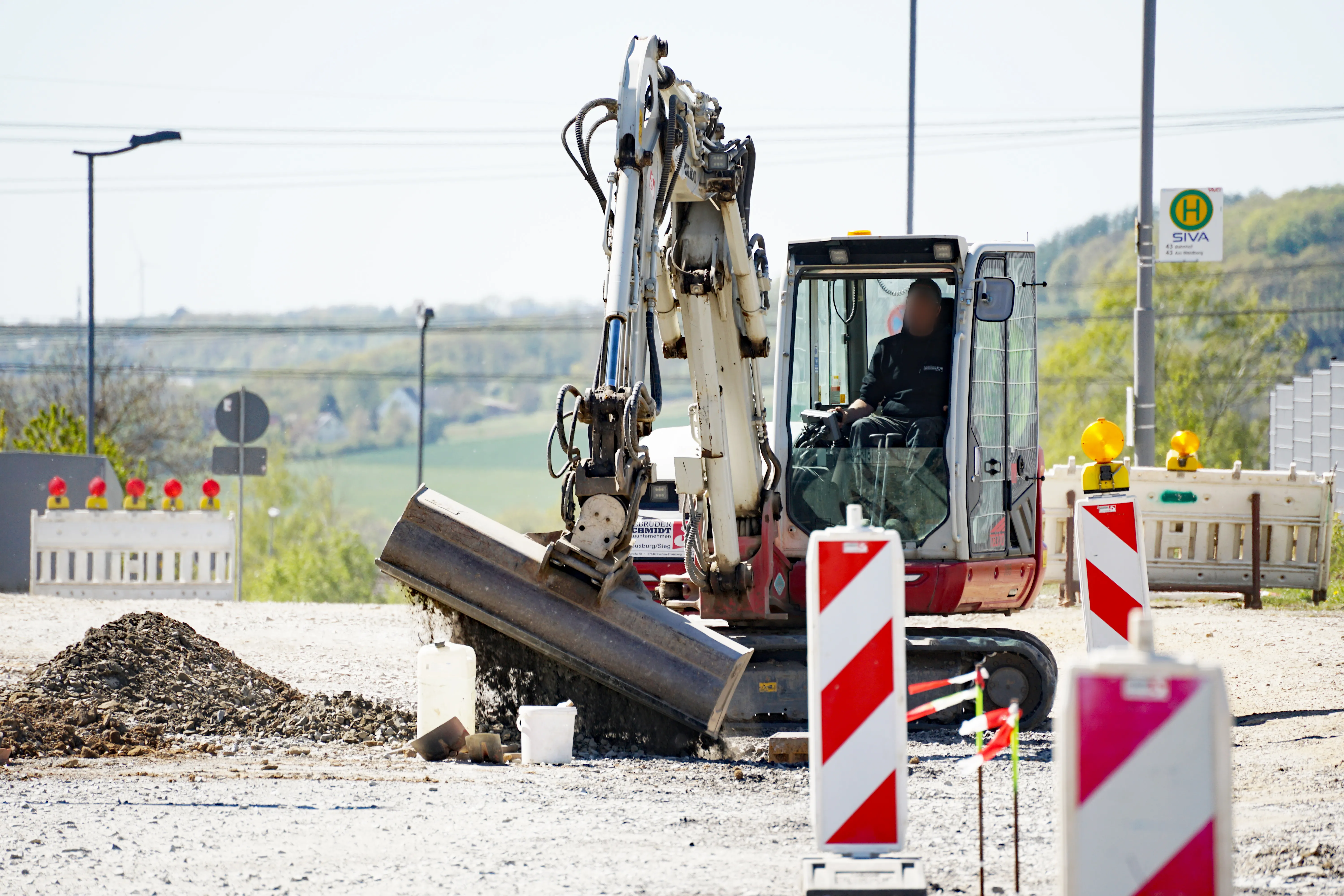 Bagger arbeitet auf einer Baustelle im Gewerbepark Rosmart, umgeben von Absperrungen und Schutzeinrichtungen.