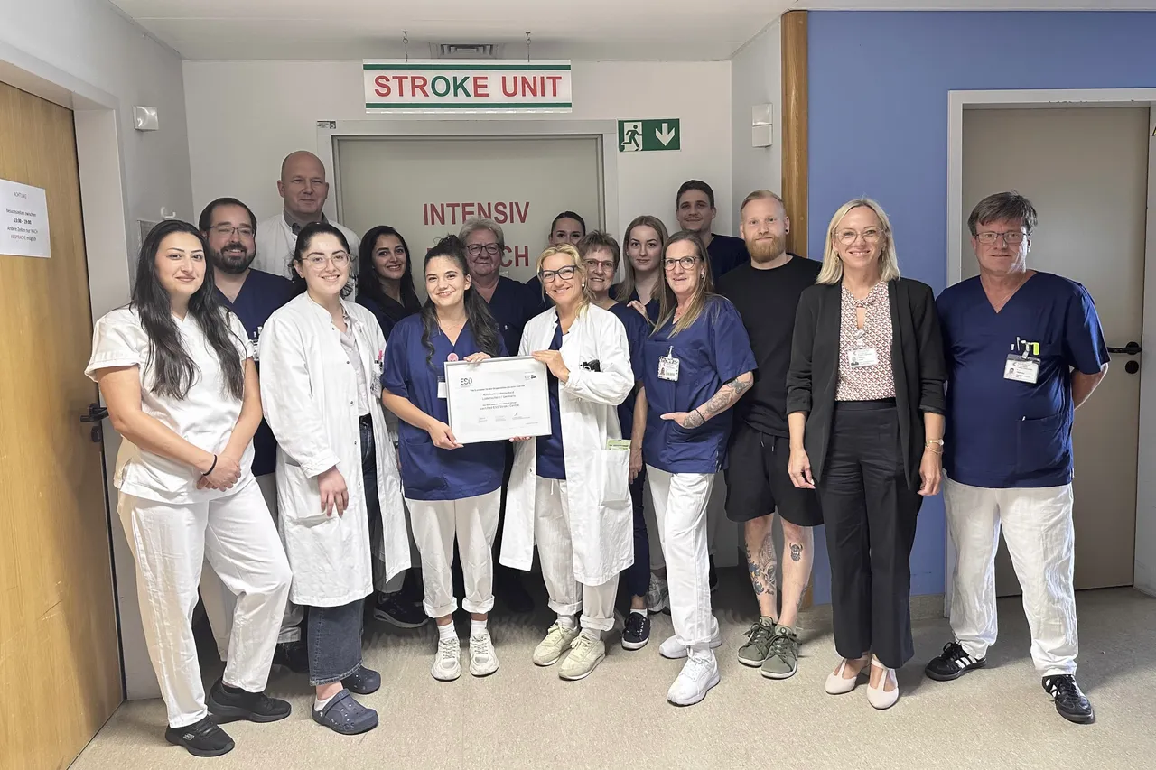 Ein Team von medizinischem Personal posiert vor der Beschilderung der „Stroke Unit“ und hält ein Zertifikat.