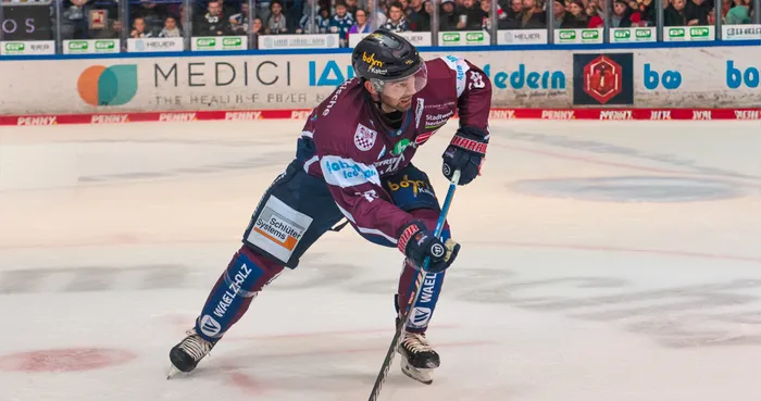 Eishockeyspieler Eric Cornell in voller Ausrüstung beim Schlittschuhlaufen auf dem Eis, mit Schläger in der Hand und Blick nach vorne gerichtet.