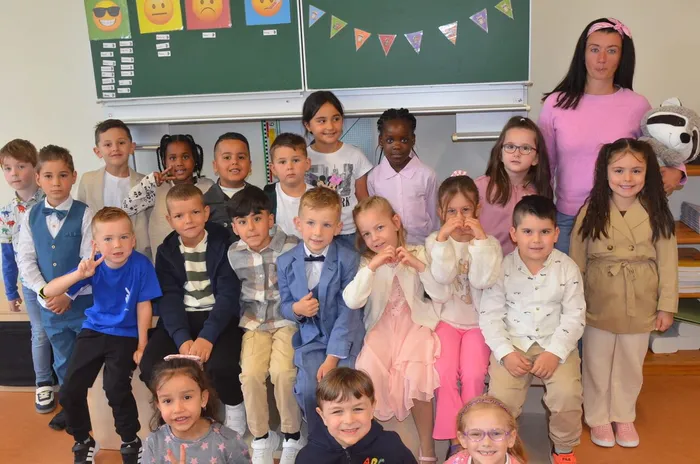 Die Schüler der Waschbären-Klasse 1b posieren gemeinsam mit ihrer Klassenlehrerin Natalie Specht in einem Klassenzimmer.