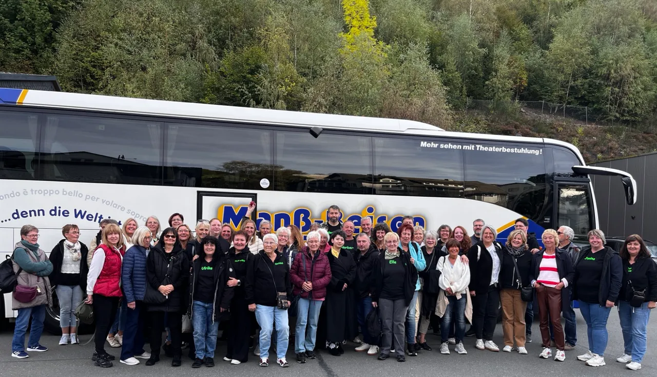 Mitglieder des TuS Oberrahmede posieren für ein Gruppenfoto vor einem weißen Reisebus mit der Aufschrift „Manß-Reisen“.
