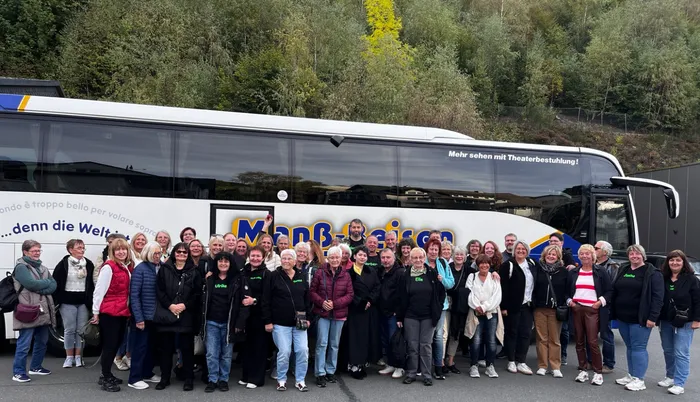 Mitglieder des TuS Oberrahmede posieren für ein Gruppenfoto vor einem weißen Reisebus mit der Aufschrift „Manß-Reisen“.