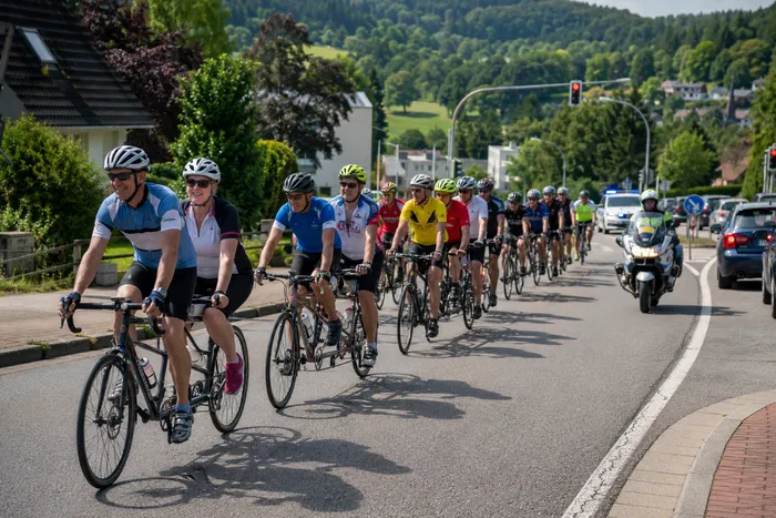 Eine Gruppe von Radfahrern fährt in einem Verband auf einer Straße.