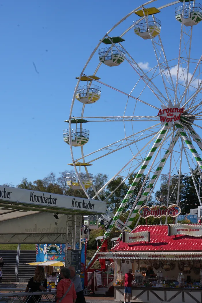 Ein großes Riesenrad über Verkaufsständen auf dem Bautz-Festival unter blauem Himmel.