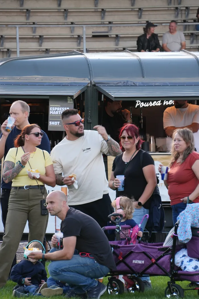 Menschen stehen vor einem Imbisswagen und essen und trinken auf dem Bautz-Festival.